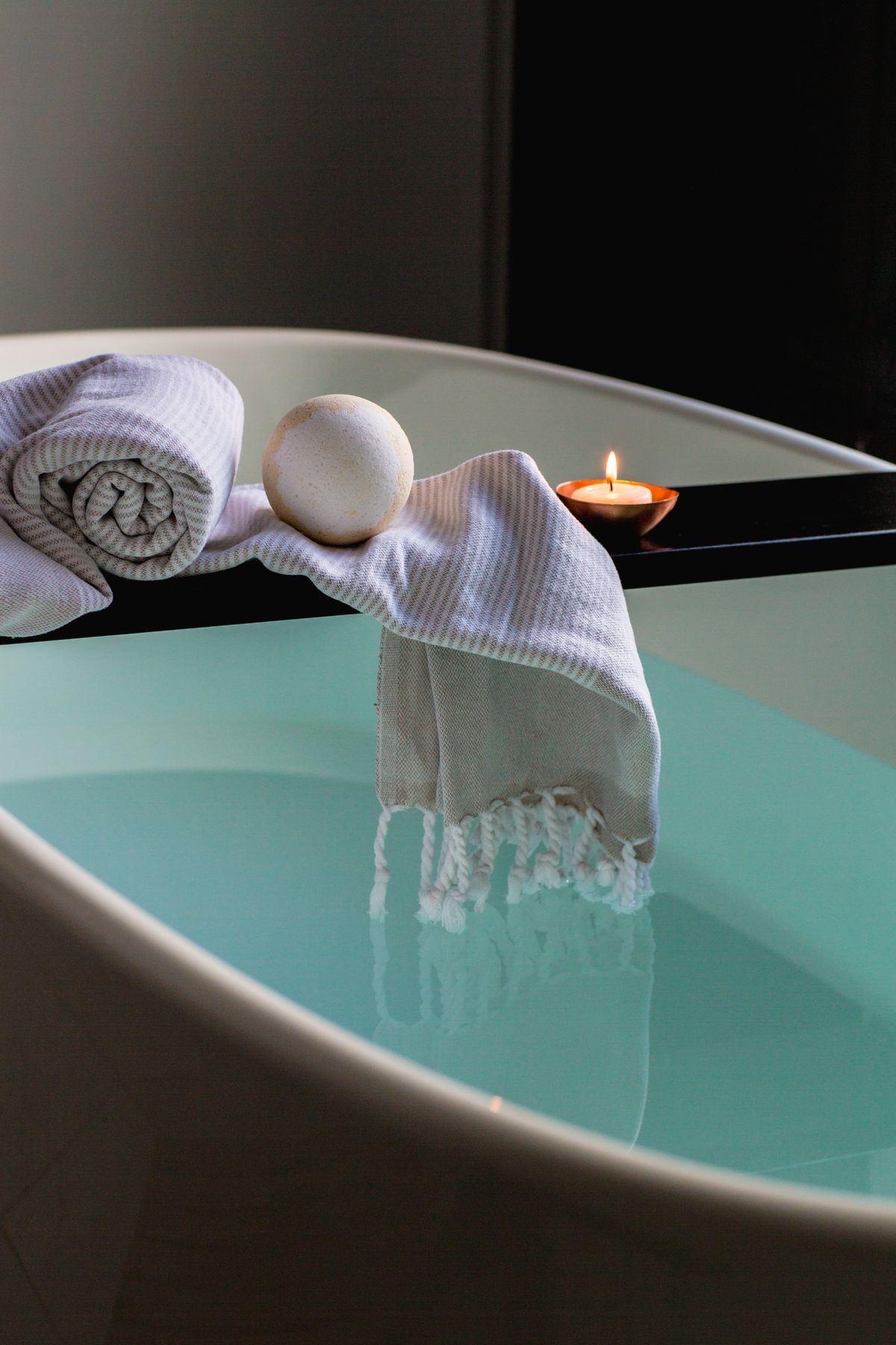 A drawn bath beside a lit candle and folded towels